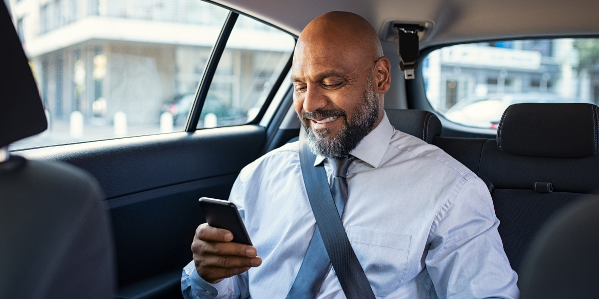 Businessman using phone while in back of car