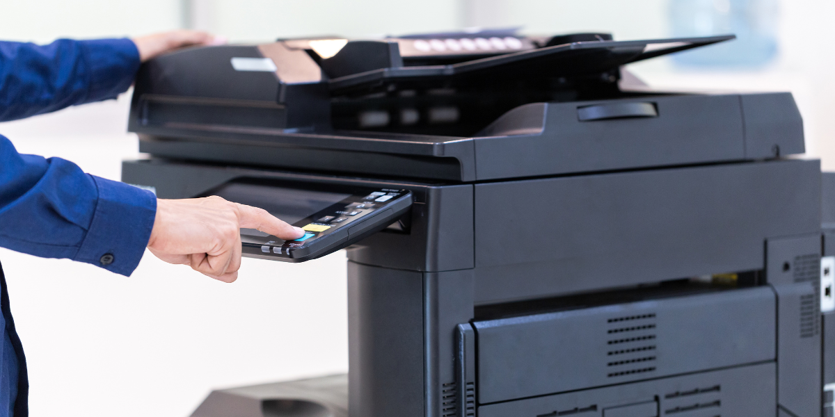Button on office printer being pressed. 