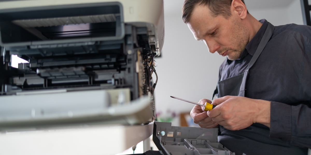 Managed print services technician working on fixing printer, 