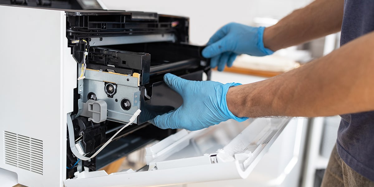 Technician hand opening printer cover to fix problem with paper jam and replace part