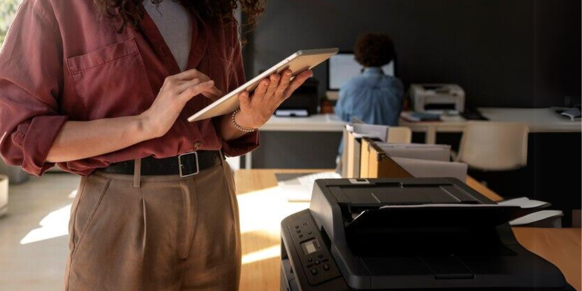 woman using tablet next to printer to perform follow me printing