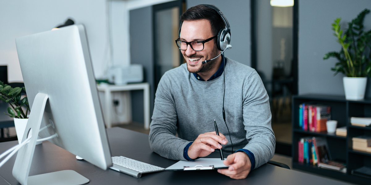 IT support specialist in front of computer helping customer over headset