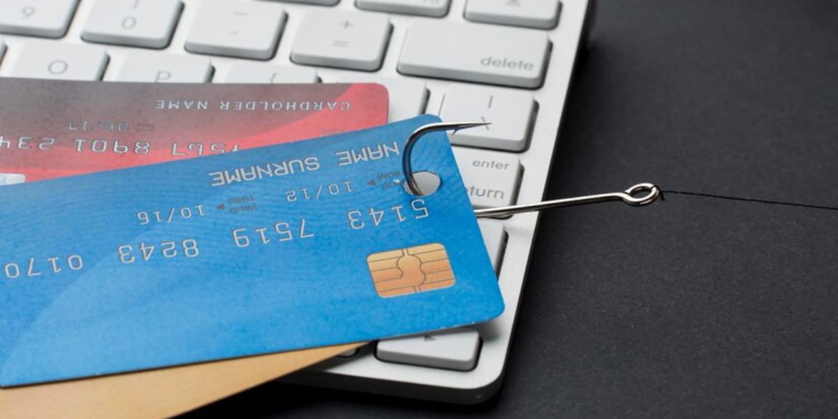 credit cards laying on keyboard hooked by fishing hook representing a phishing attack.
