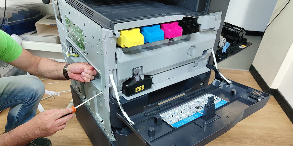 Man fixing the printer with open lid and visibly colorful ink containers